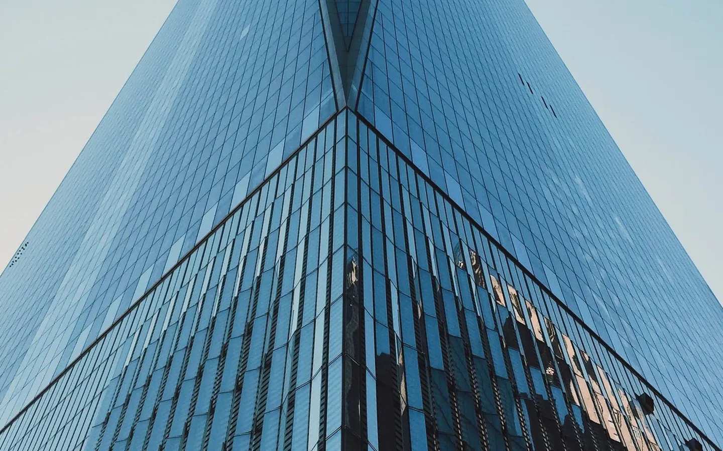 Glass tower viewed from below, rising into the sky