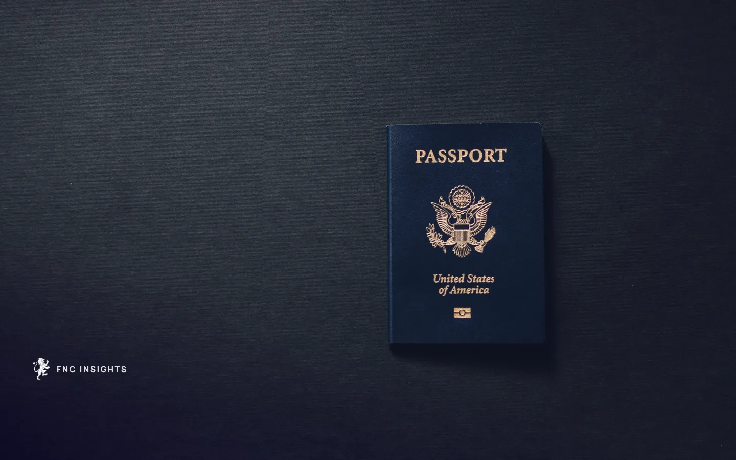 A United States passport lying closed on a dark charcoal surface