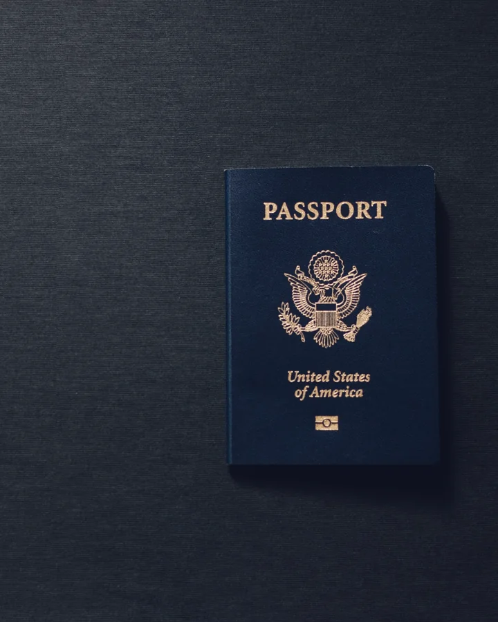 A United States passport lying closed on a dark charcoal surface